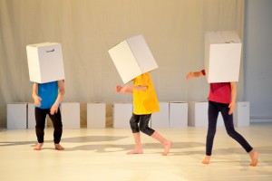 Tanzende Kinder bei Bewegungsexperimenten mit weißen Kartons.