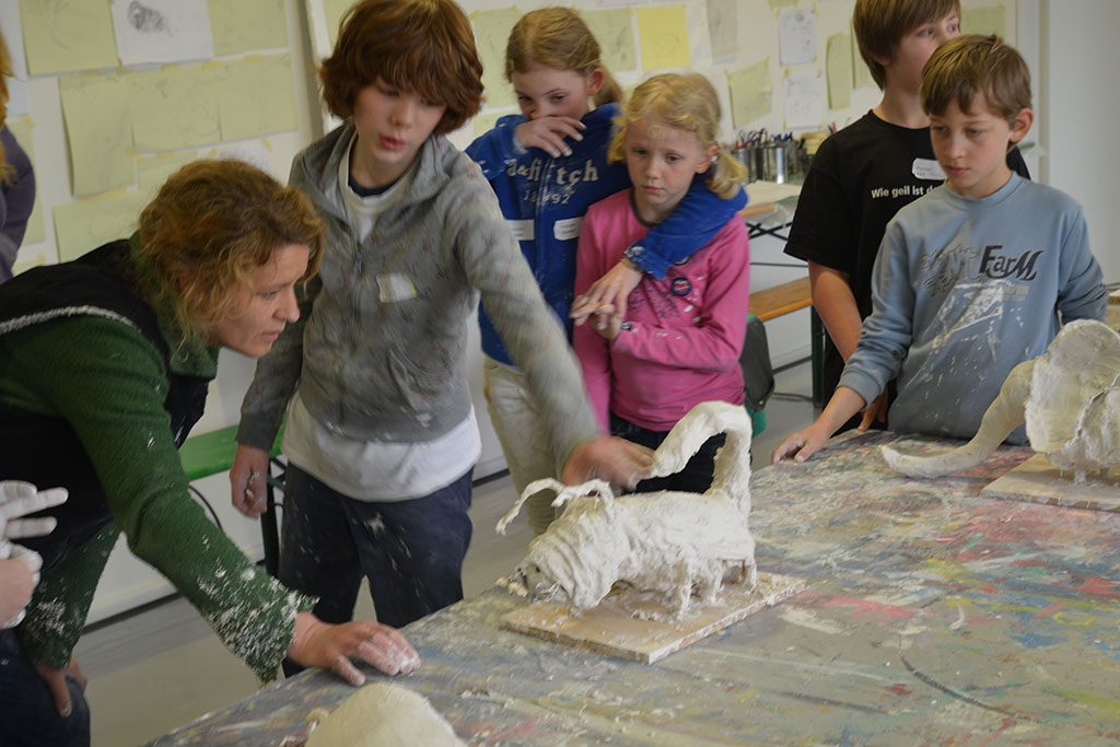 Eine Künstlerin betrachtet mit einem Kind ein Werkstück.